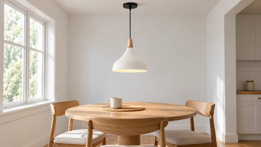 A white bell pendant with a wood neck centered above a round oak breakfast table in a bright dining nook.